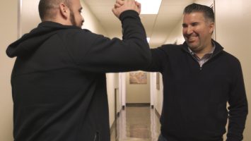 Basilio Santangelo (left) and Paul Diaz (right) high five as they pass in the hallway at The Men’s Clinic at UCLA. Along with another friend, they made appointments to get vasectomies on the same day so they could recuperate together while watching sport